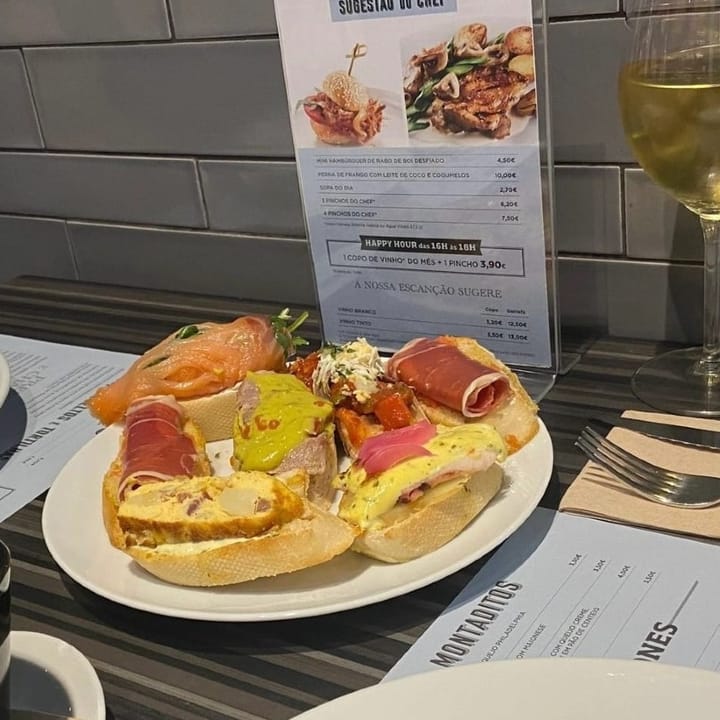 A plate of various tapas and a large glass of wine