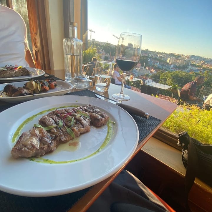 View over Lisbon from a window table, with a 250g ribeye steak in the foreground